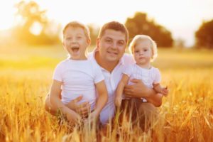 Family Relaxing In Summer Harvested Field